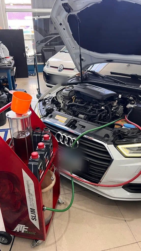 Máquina de diálise de fluido ligada por duas mangueiras a um Audi com o capô aberto, durante a troca do óleo do câmbio automático.