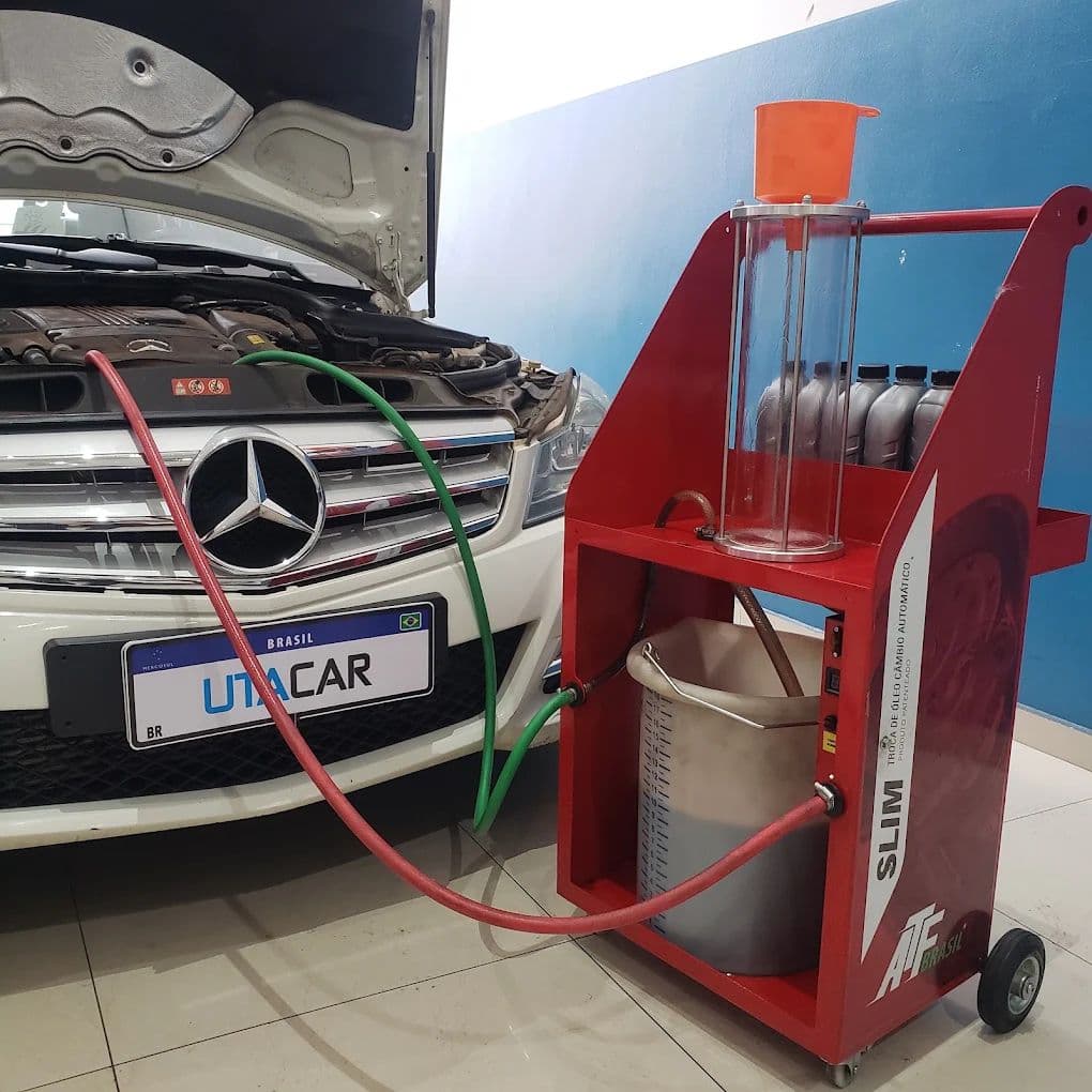 Máquina de diálise vermelha ligada a uma Mercedes-Benz com o capô aberto, com a placa de cobertura da UTACAR no lugar da placa do cliente.
