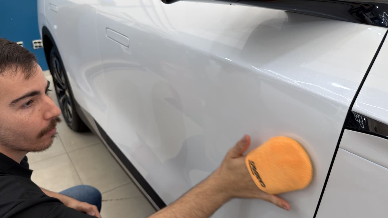 Técnico aplica o revestimento cerâmico na porta do carro com o aplicador de espuma.