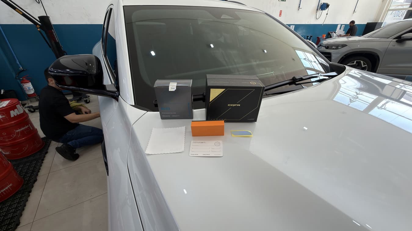 Caixas do revestimento CARPRO sobre o capô do carro, com técnico da Utacar trabalhando ao lado durante a aplicação.