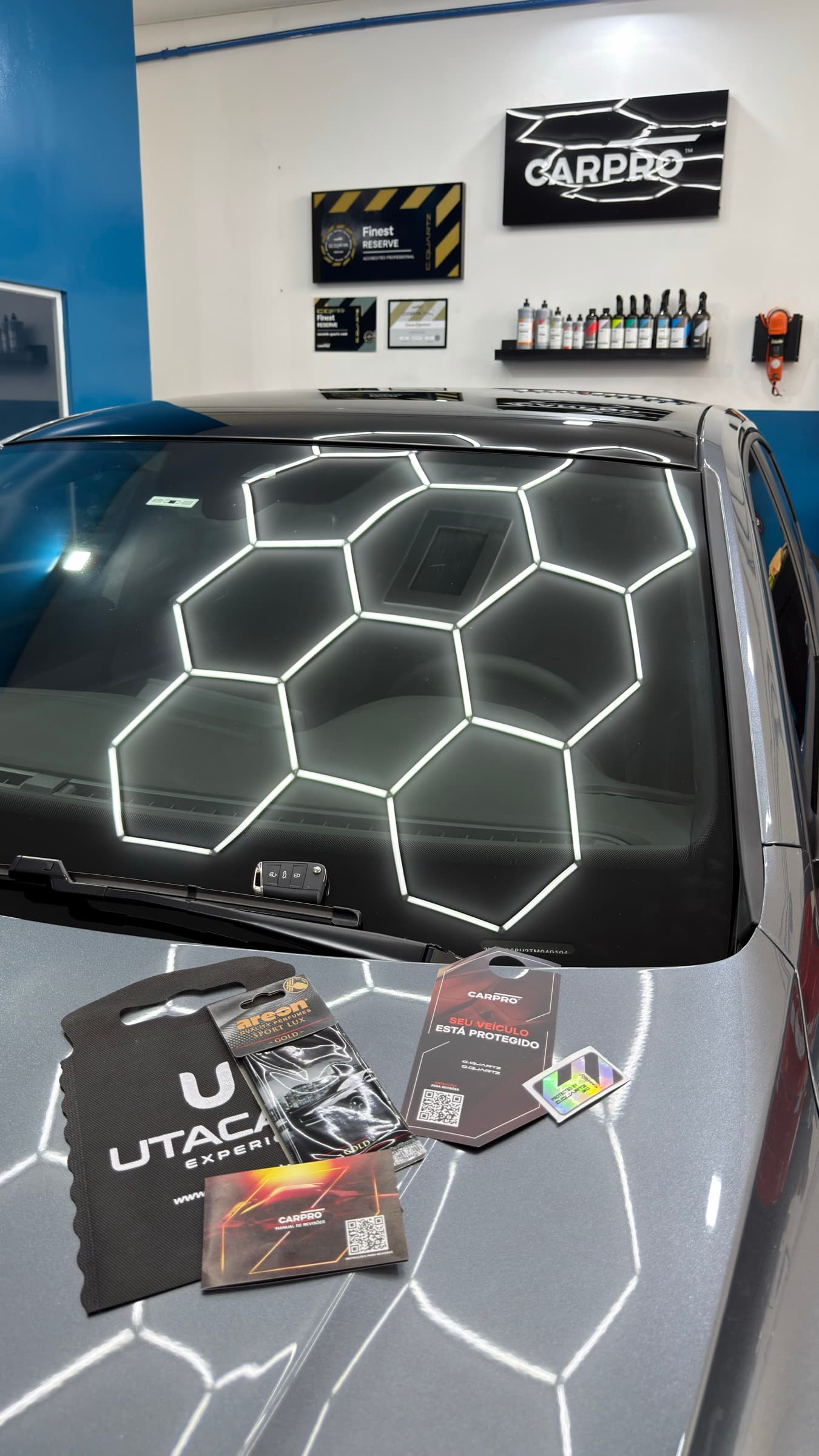 Sacola de entrega da Utacar e cartão da CARPRO apoiados sobre o carro pronto, com a placa Finest Reserve na parede ao fundo.