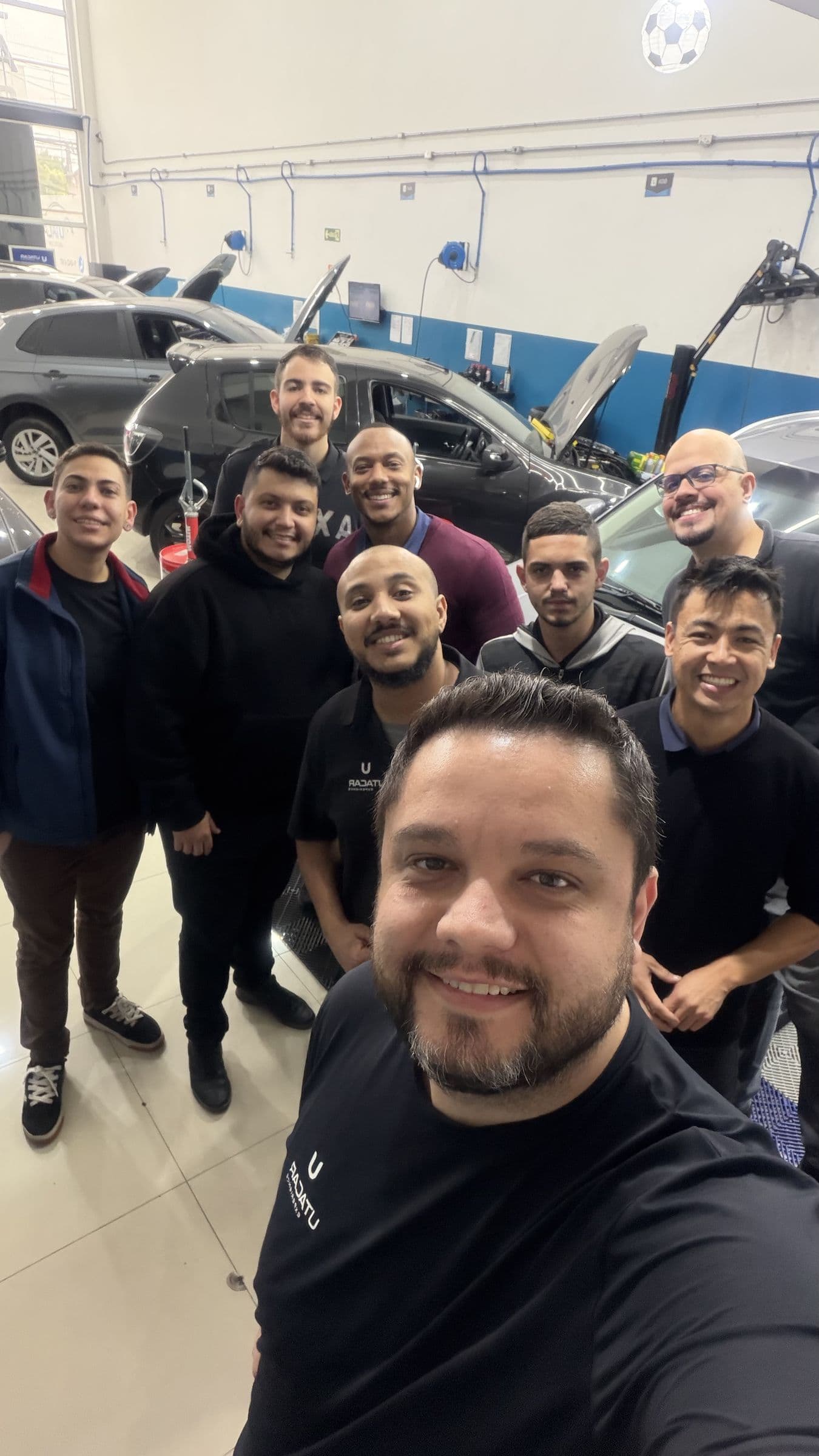 A equipe da Utacar reunida dentro da oficina, com carros em atendimento ao fundo.
