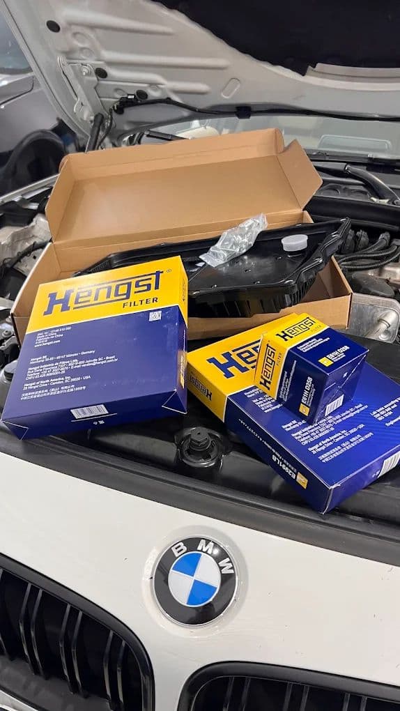 Caixas de filtros Hengst empilhadas sobre o motor de um BMW com o capô aberto.
