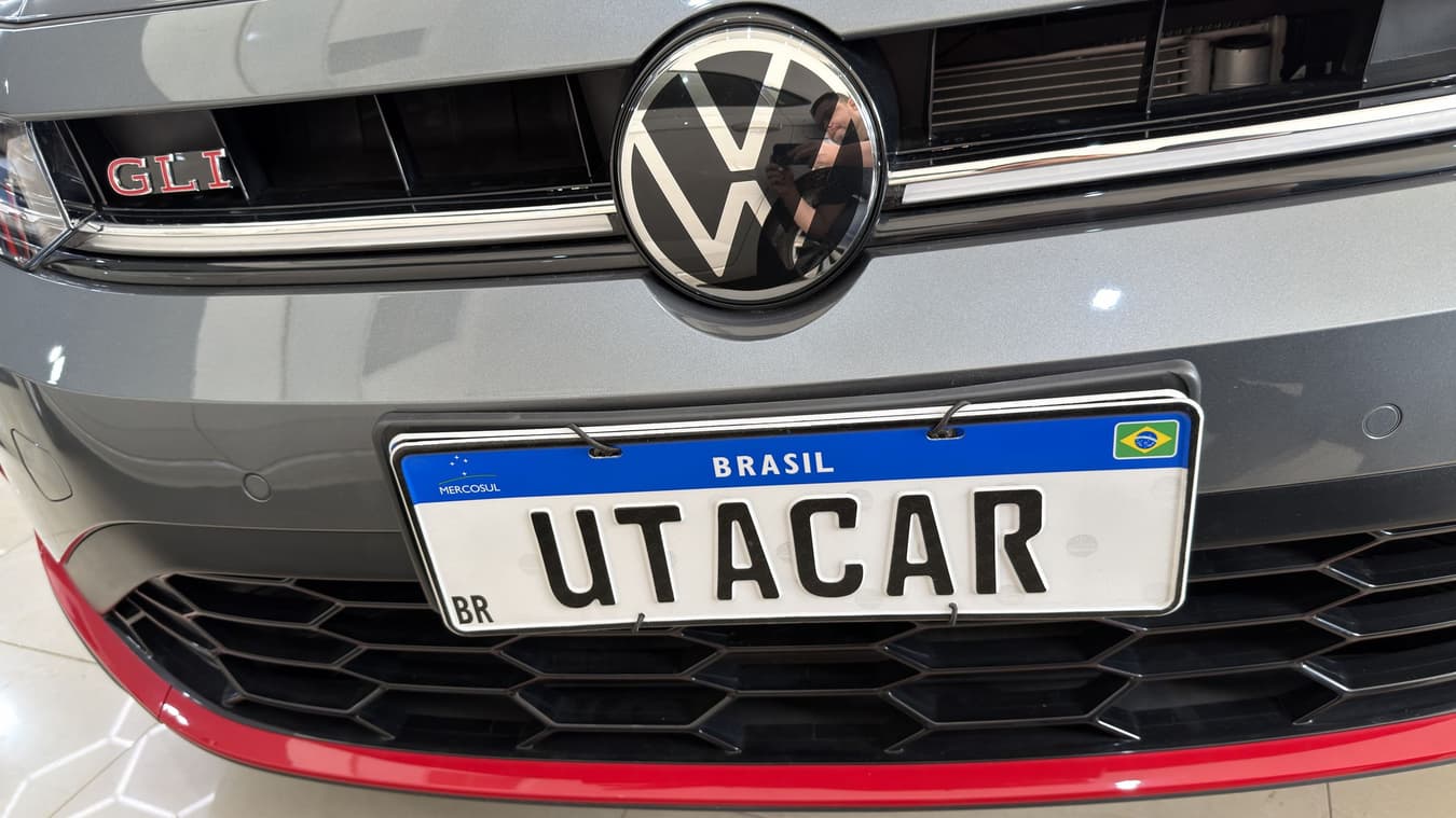 Placa de cobertura escrita UTACAR instalada na frente de um Volkswagen, no lugar da placa real do cliente.